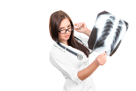 Young female doctor with a stethoscope looking at the xray picture of lungs on whiteの写真素材