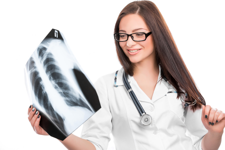 Young female doctor with a stethoscope looking at the x-ray picture of lungs on whiteの写真素材