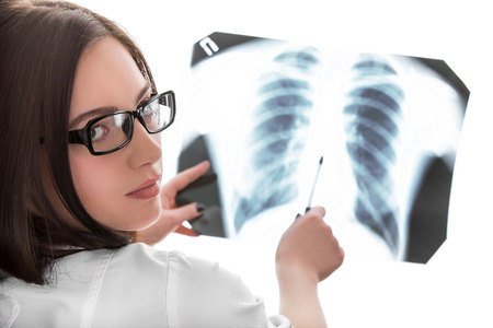 Young female doctor looking at the x-ray picture of lungs on white