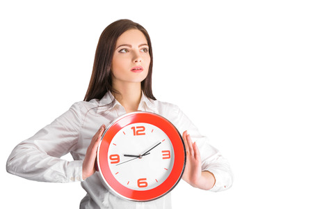 Portrait of beautiful young business woman holding in hands clock, isolated on white background, discipline and punctual conceptの写真素材