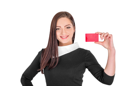 Close-up portrait of young smiling business woman holding red credit card isolated on white backgroundの写真素材