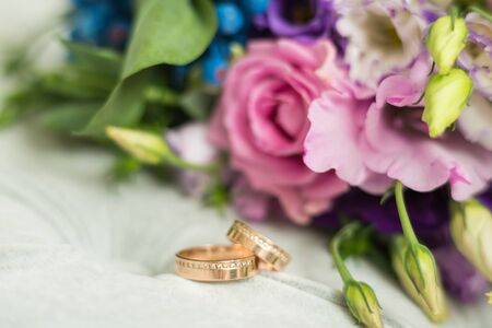two wedding rings and a bouquet of flowersの写真素材
