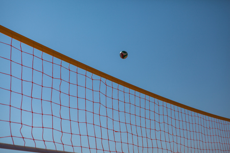 Volleyball Ball Over Net On Background Of Blue Summer Sunny Sky. Ball Flying Through Air On Beachの写真素材
