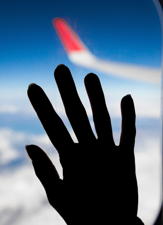photo of woman hand on a aeroplane windowの写真素材