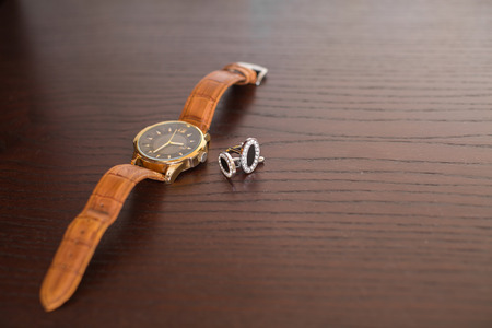 black cufflinks and watch on wooden tableの写真素材