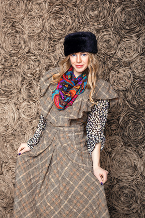 beautiful attractive blonde girl in a brown dress and black fur hatの写真素材