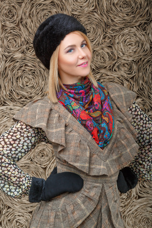 beautiful attractive blonde girl in a brown dress and black fur hatの写真素材