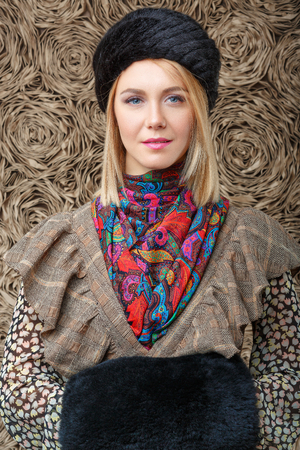 beautiful attractive blonde girl in a brown dress and black fur hatの写真素材