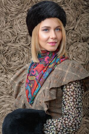 beautiful attractive blonde girl in a brown dress and black fur hatの写真素材