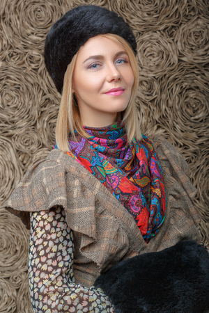 beautiful attractive blonde girl in a brown dress and black fur hatの写真素材