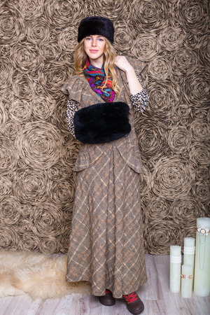 beautiful attractive blonde girl in a brown dress and black fur hatの写真素材