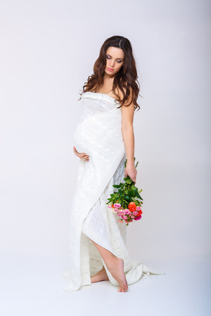 beautiful pregnant woman and a basket of colourful flowers.の写真素材