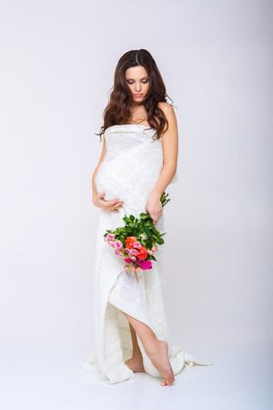 beautiful pregnant woman and a basket of colourful flowers.の写真素材