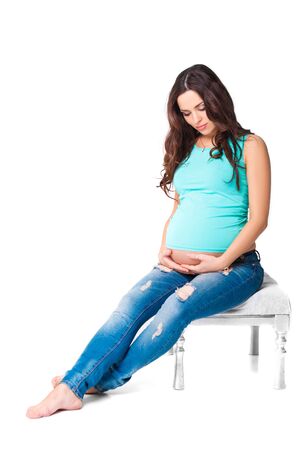 beautiful brunette pregnant woman. attractive mom in the blue t-shirt and jeansの写真素材