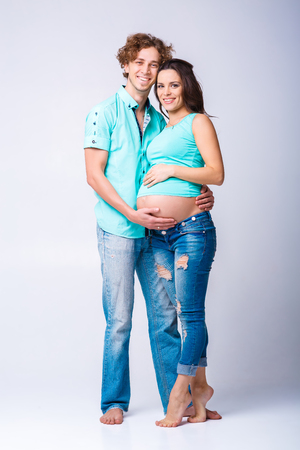 beautiful pregnant woman with her husband. future mother and father in blue t-shirt and jeans. happy familyの写真素材