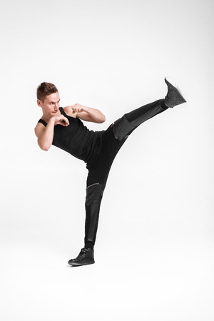 attractive young man kicking foot forward, on a white backgroundの写真素材