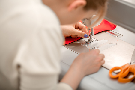 beautiful woman seamstress sew on the sewing machine clothes. sewing workshopの写真素材