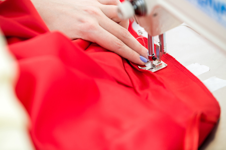seamstress sewing on sewing machine, clothes. sewing workshop. hand and sewing machine closeupの写真素材