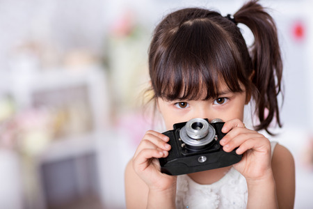 cute little girl holding an old camera. child taking pictures on an old cameraの写真素材