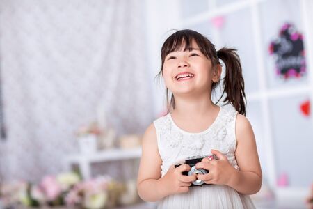smiling little girl in a white dress  holding an old camera. child taking pictures on an old cameraの写真素材