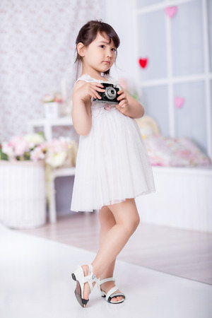cute little girl holding an old camera. child taking pictures on an old cameraの写真素材