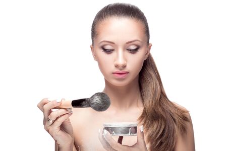 beautiful young woman picking up the powder on the brush. the final stage of makeupの写真素材