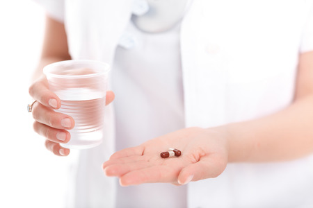 doctor holding a pill and a glass of water, close-upの写真素材