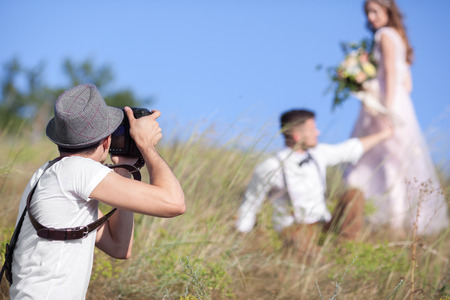 a wedding photographer takes pictures of the bride and groom in nature, the photographer in actionの写真素材