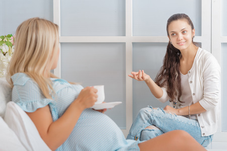 pregnant woman talking with a friend and have funの写真素材