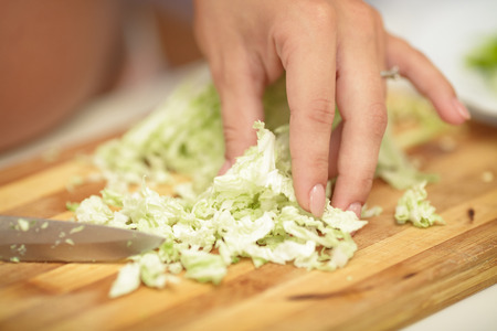 pregnant woman cuts cabbage on wooden Board in the kitchen. close-upの写真素材