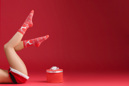 Mrs santa claus legs in Christmas stockings with christmas gift on red backgroundの写真素材