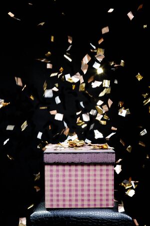 Red gift box and confetti. Black background. Gifts for Christmas.の写真素材
