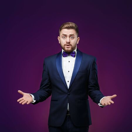 Handsome man in tuxedo and bow tie is surprised, throws his hands. compere in fashionable, festive clothingの写真素材