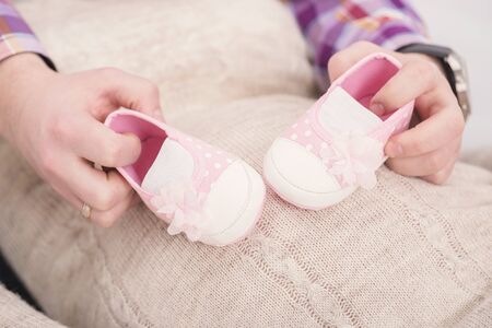 pink booties for newborn baby in hands of dad. pregnancyの写真素材