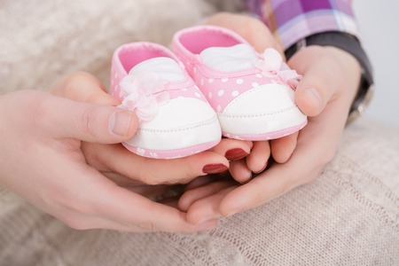 pink booties for newborn baby in hands of mum and dad. pregnancyの写真素材
