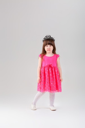 beautiful little girl in pink Princess dress with crown on grayの写真素材
