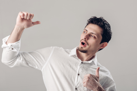portrait of ahandsom smiling Brunet man in shirt showing thumbs up gesture on gray background. soft lightの写真素材