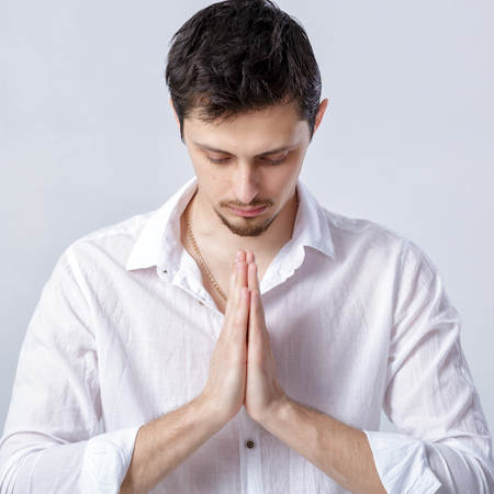 portrait of attractive man with dark hair in white shirt in yogaの写真素材