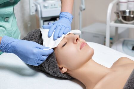cosmetologist cleanses skin of woman after applying mask. cosmetの写真素材