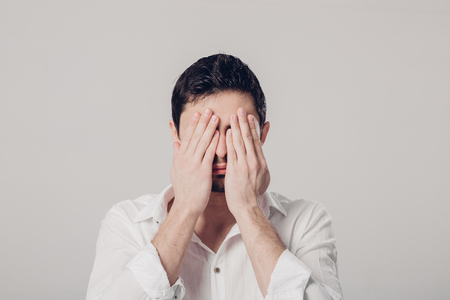 portrait of  man in white shirt closes his eyes with hands on grの写真素材