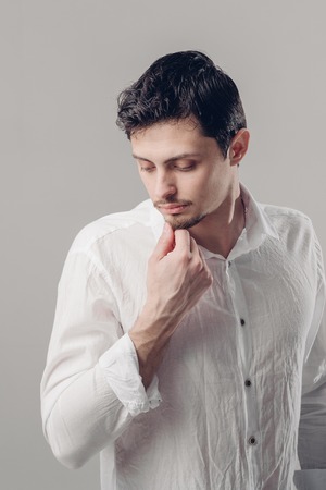 portrait of handsome young man with dark hair in white shirt onの写真素材