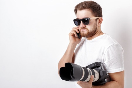 young professional photographer in white shirt holds digital camの写真素材