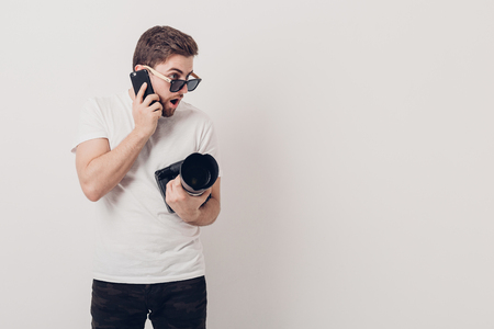 young professional photographer in white shirt holds digital camの写真素材