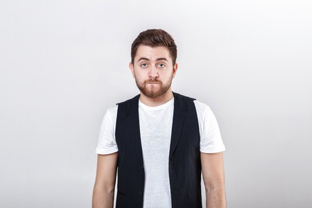 portrait of handsome pensive brunette man in white shirt on gray background. guy thinksの写真素材