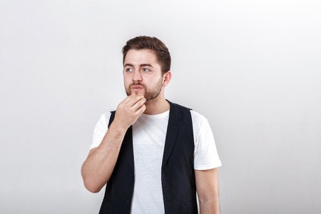 portrait of handsome pensive brunette man in white shirt on gray background. guy thinksの写真素材