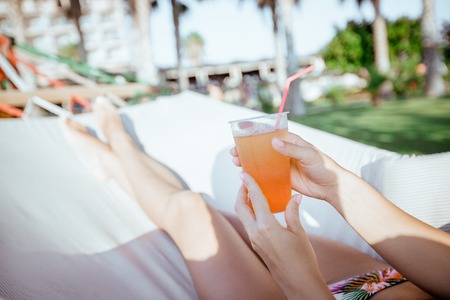 woman holding cocktail in the hammockの写真素材