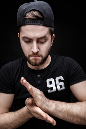 portrait of handsome young man in black shirt and cap on black background. rapperの写真素材