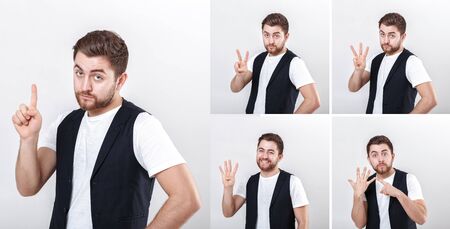 portrait of young attractive surprised brunette man in white shirt on gray background. surprising factの写真素材