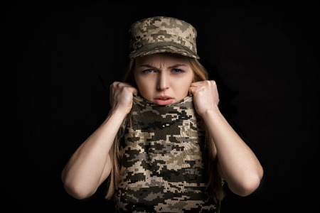 portrait of scared woman soldiers in military attire on black backgroundの写真素材