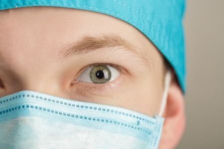 male surgeon in mask looking at camera on grey background, close upの写真素材